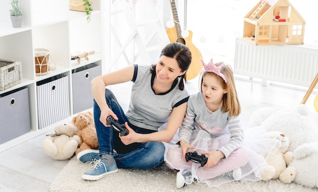 Menina jogando videogame com a mãe