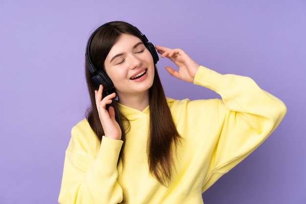 Menina jovem adolescente sobre parede roxa, ouvir música e cantar