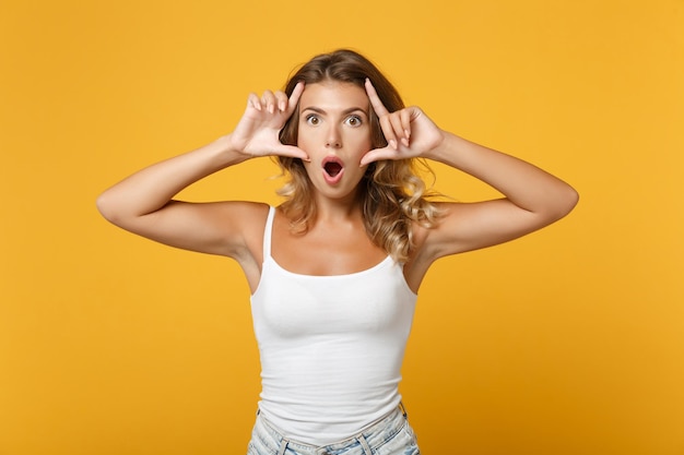 Menina jovem chocada em roupas casuais leves posando isolado no retrato de estúdio de fundo de parede laranja amarela. Conceito de estilo de vida de pessoas. Mock up espaço de cópia. Mantendo a boca aberta, esticando as pálpebras.