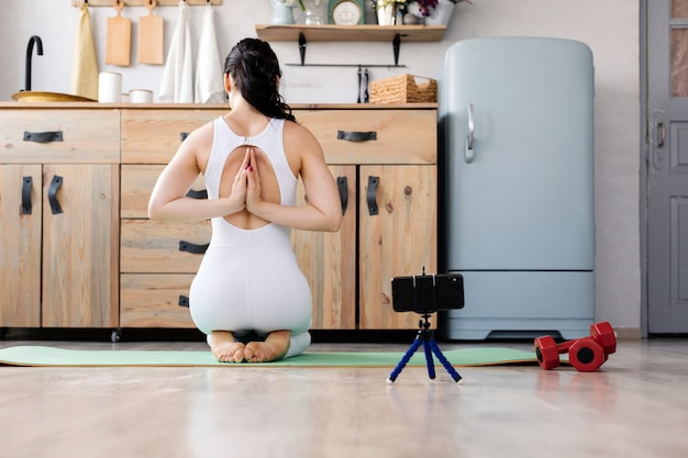 Menina jovem fazendo exercícios de fitness ioga em casa