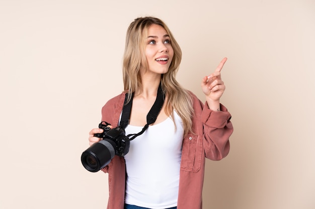 Menina jovem fotógrafo sobre parede apontando com o dedo indicador uma ótima idéia