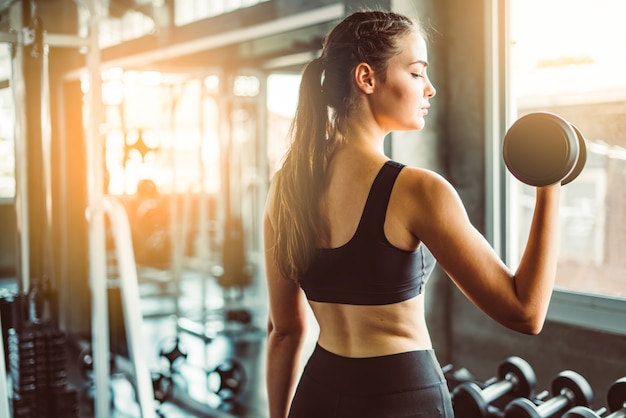 Menina jovem, jogando dumbbell