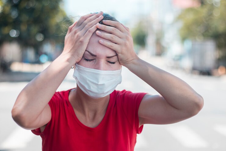 Foto menina, jovem mulher europeia em máscara médica estéril protetora no rosto, sofrendo de dor de cabeça, segurando a cabeça com as mãos. sintomas de vírus, conceito de pandemia de coronavírus chinês. 2019 ncov