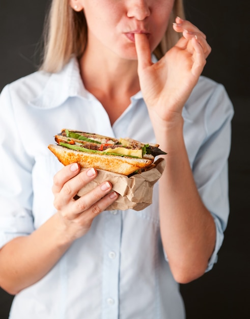 Menina lambendo os dedos segurando um sanduíche delicioso