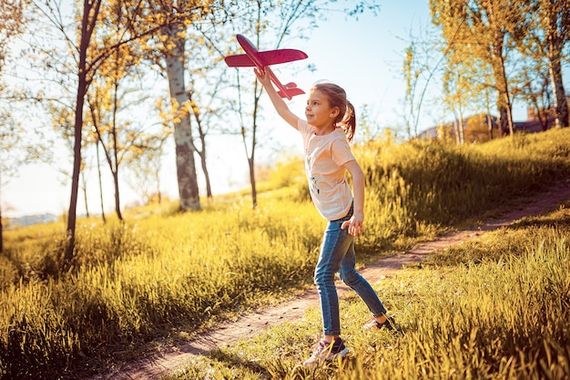 Menina lança um avião de brinquedo no ar no parque