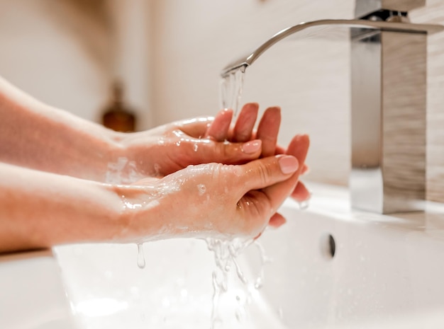 Menina lavando as mãos com sabão no banheiro