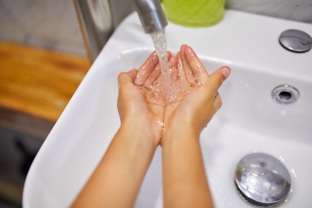 Menina lavando as mãos com sabonete no banheiro