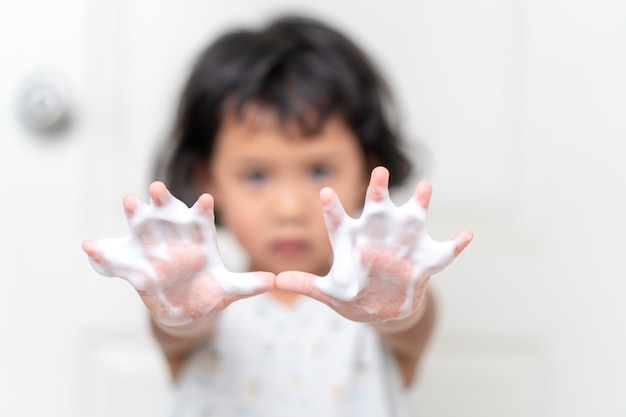 Menina lavando as mãos para evitar vírus, germes e bactérias no banheiro