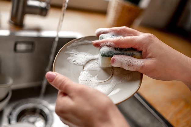 Menina lavando pratos na cozinha em casa