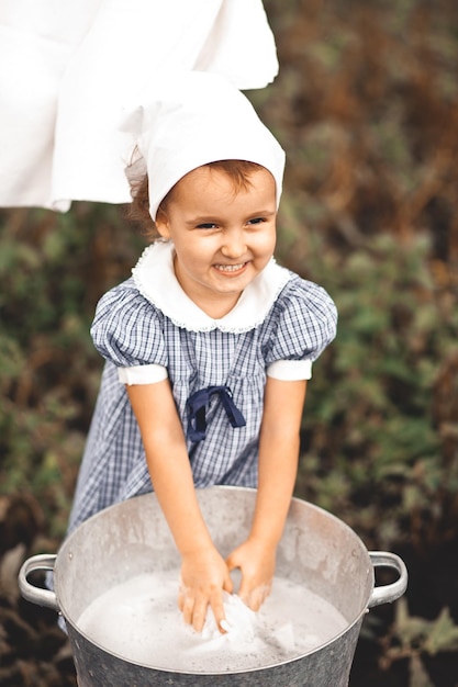 Menina lavando roupas à mão em uma bacia de estanho. estilo retrô. lavagem das mãos.