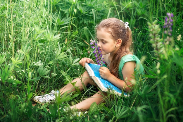 menina lê um livro na natureza no verão