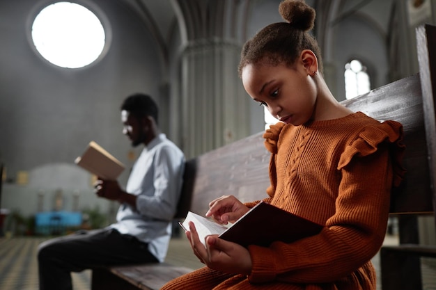 Menina lendo a bíblia na igreja