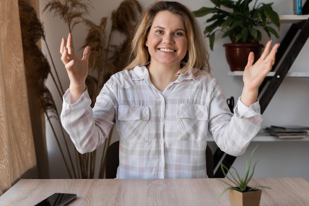 Menina lendo sms on-line em um telefone inteligente sentado em uma mesa em casa com uma luz quente de uma janela ao fundo