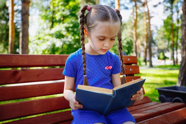 Menina lendo um livro ao ar livre.