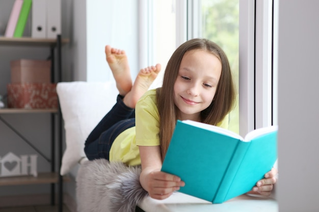 Menina lendo um livro em casa