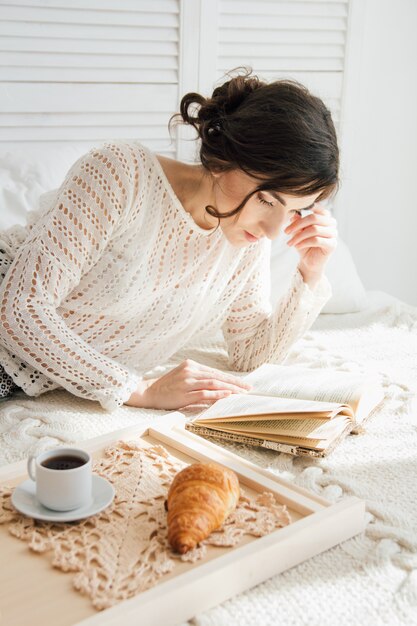 Menina lendo um livro no café da manhã