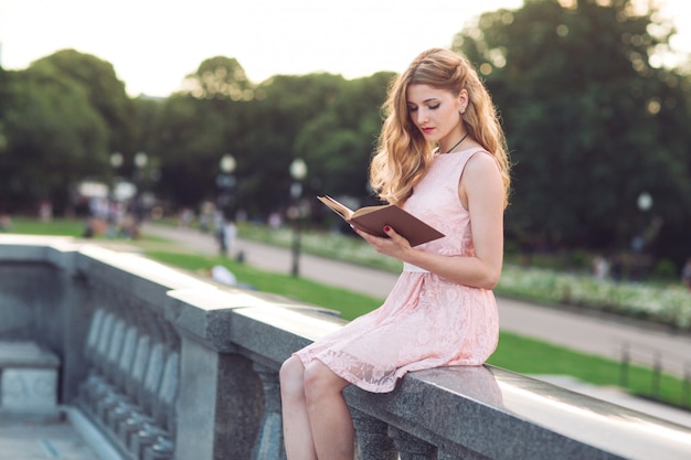 Menina lendo um livro no parque.