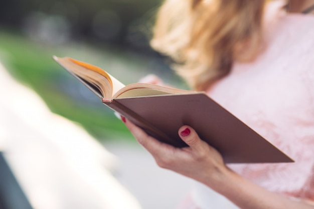 Foto menina lendo um livro no parque.