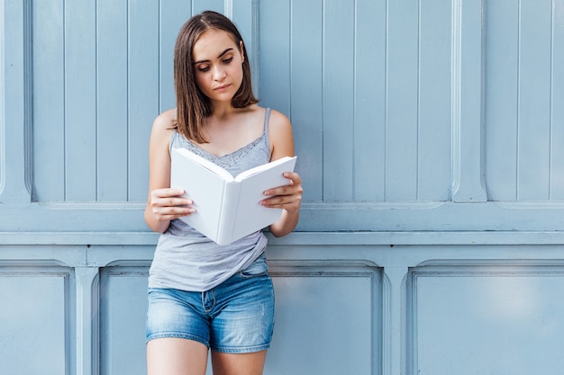 Menina lendo um livro sobre fundo cinza azulado