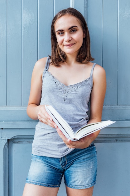 Menina lendo um livro sobre fundo cinza azulado