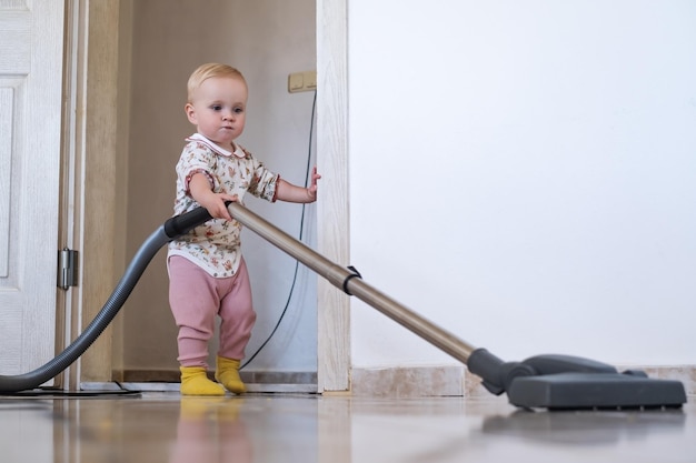 Menina limpando o tapete com aspirador de pó