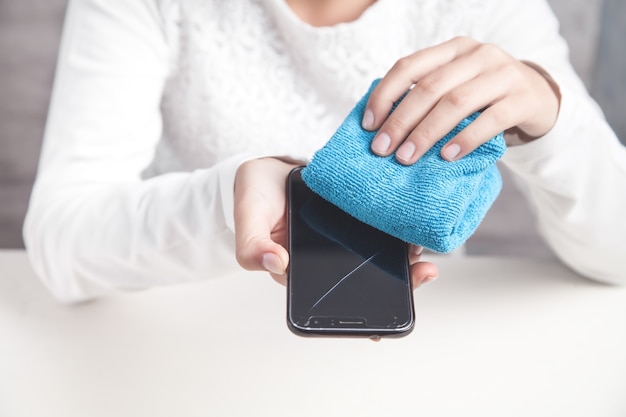 Foto menina limpando seu smartphone no escritório.