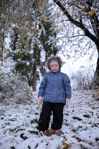 Foto menina linda com roupas de inverno sozinha no meio de uma floresta nevada