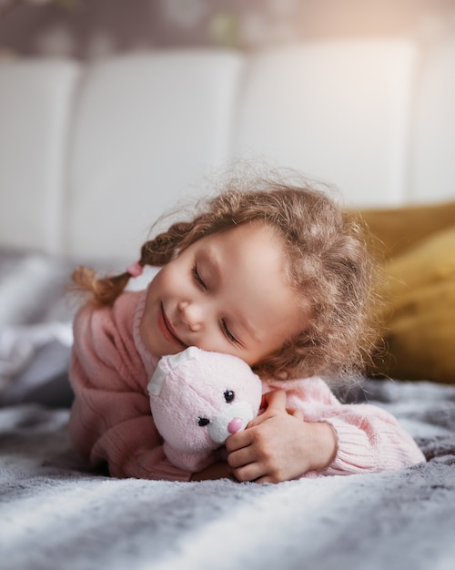 Menina linda com um brinquedo macio deitada de olhos fechados