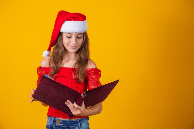 Menina linda criança caucasiana com um livro aveludado vermelho, lendo histórias de Natal.