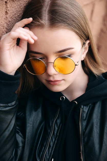Menina linda criança elegante em óculos de sol amarelos na rua da cidade