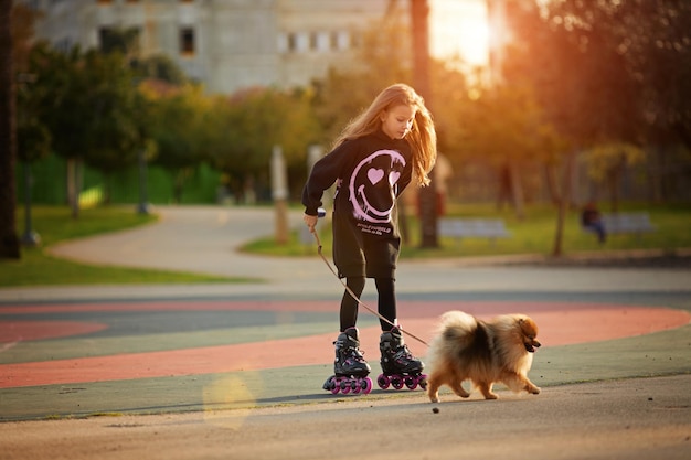 Menina linda de patins caminha com um cachorrinho no parque