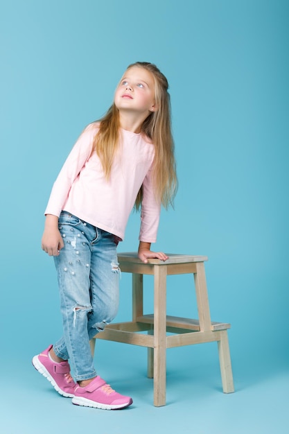 Menina linda de suéter rosa e jeans posando no estúdio