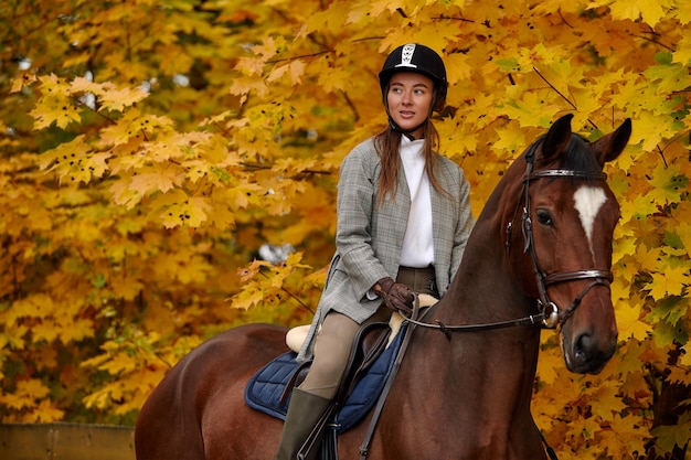 Menina linda de vestido andando a cavalo na floresta de outono