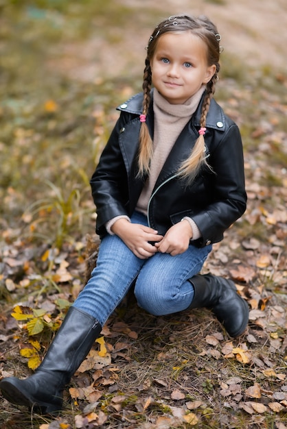 Menina linda e feliz com roupas da moda casuais no outono parque natural