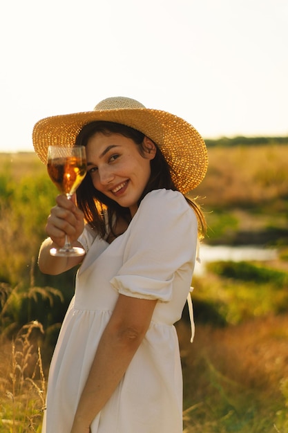 Menina linda em um vestido branco fazendo um piquenique com uma taça de champanhe ou vinho branco