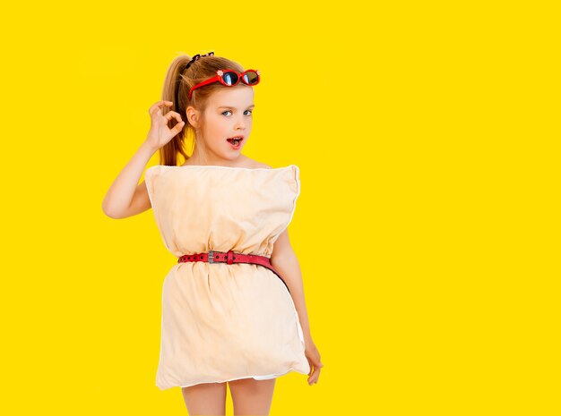 Menina linda em um vestido feito de travesseiros em uma quarentena de fundo amarelo