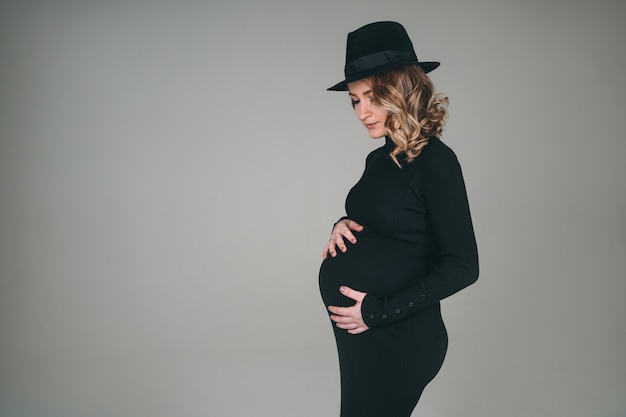 Menina linda grávida em um vestido preto. Uma mulher está esperando o nascimento de um filho.