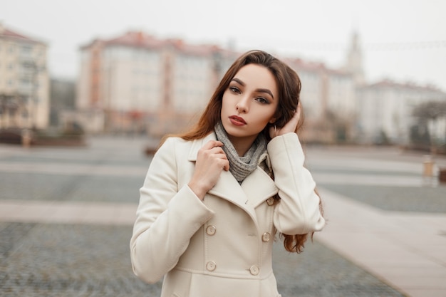 Menina linda jovem modelo com casaco da moda e uma camisola posando do lado de fora da cidade em dia de inverno