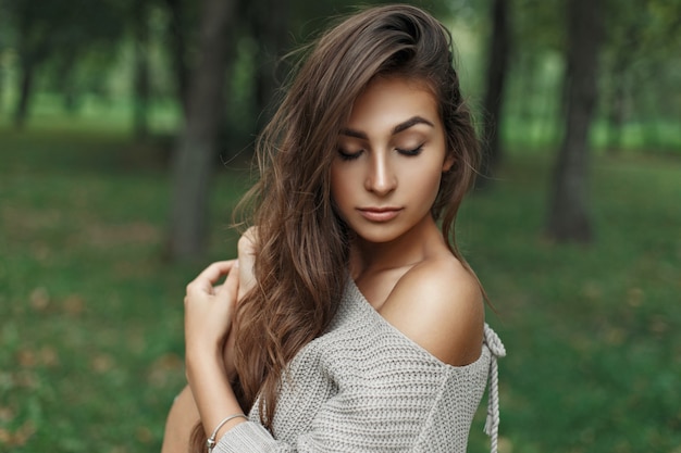 Menina linda jovem modelo com penteado em uma camisola de malha no parque