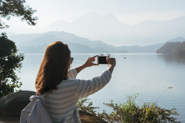 Menina linda jovem tirar uma foto da vista em frente na trilha de bicicleta no lago pela manhã. Pessoas ativas. Ao ar livre