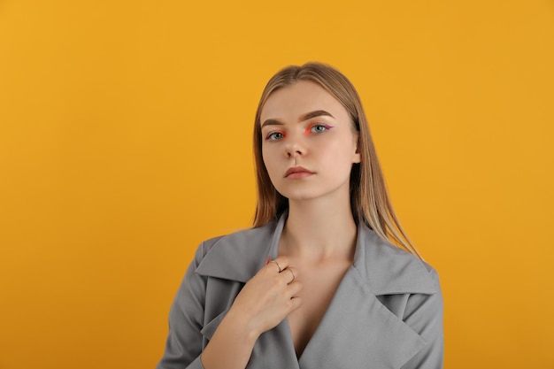 Menina linda modelo com capa de outono em fundo amarelo