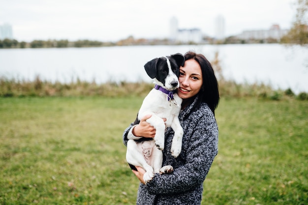 Menina linda passeando com o cachorro. Fêmea bonito que joga com os filhotes de cachorro ao ar livre na natureza. Proprietário com adoráveis pequenos caninos jovens com olhos de pena.