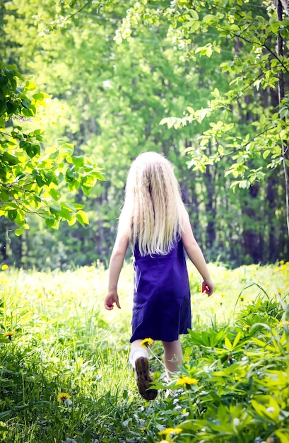 Menina loira bonitinha no prado no parque de verão