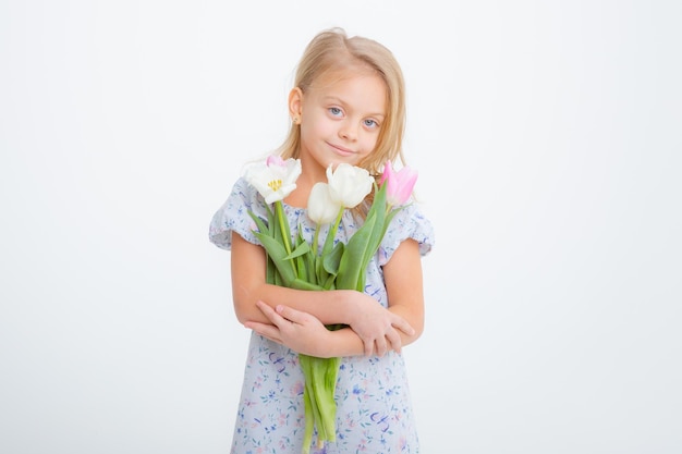 Menina loira bonitinha segurando um buquê de flores da primavera em um fundo branco