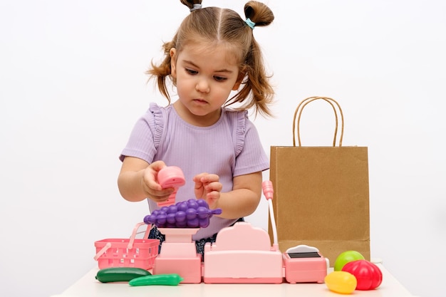 Menina loira brinca na loja pesa frutas em balanças de brinquedos coleta  pedido em pacote de artesanato caixa registradora infantil jogos caseiros  para crianças pedidos de comida on-line conceito de entrega de