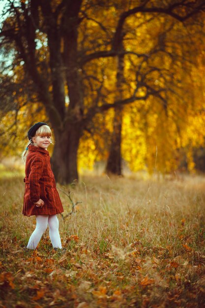 menina loira com casaco vermelho andando na floresta