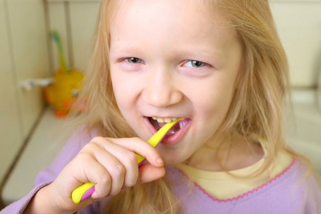 Menina loira com escova de dentes