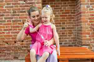 Foto menina loira com implante coclear brincando com sua mãe ao ar livre com deficiência auditiva surda e
