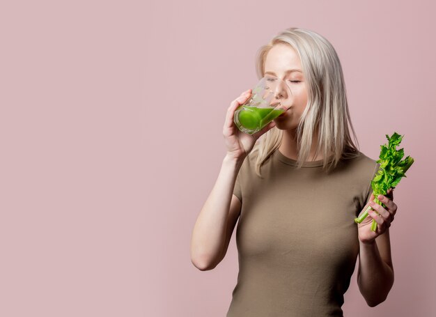 Menina loira com suco de aipo rosa