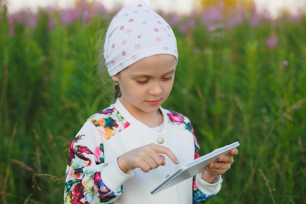Menina loira com tablet digital sobre a natureza